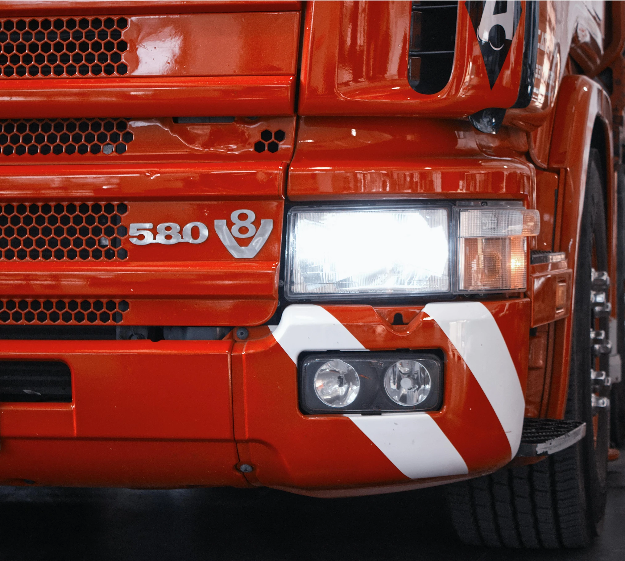 the headlights of an orange truck with white stripes