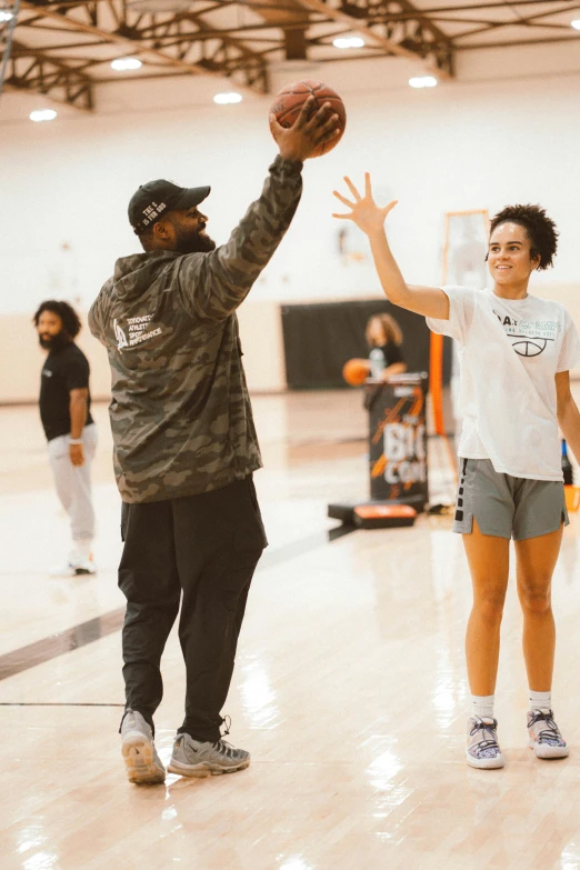 a young man reaches up for a basketball while another player watches