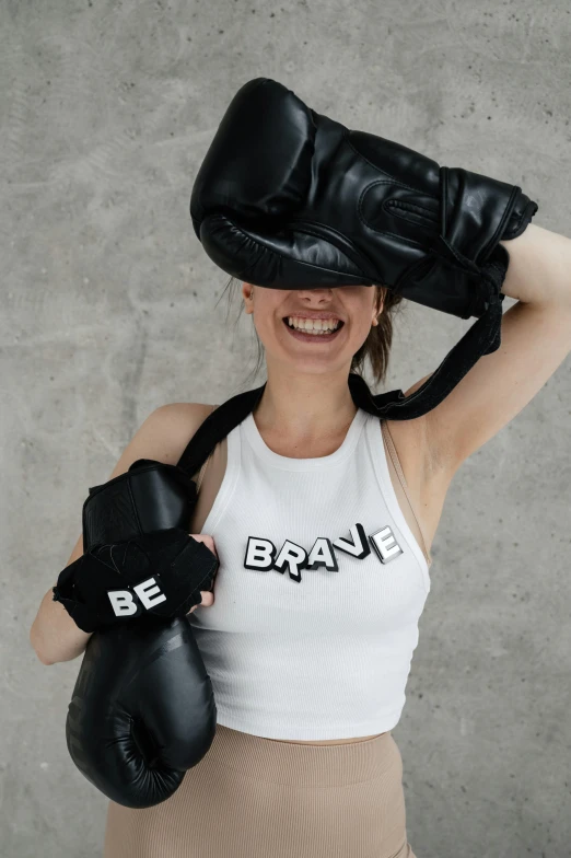 a smiling woman wearing boxing gloves on top of her head