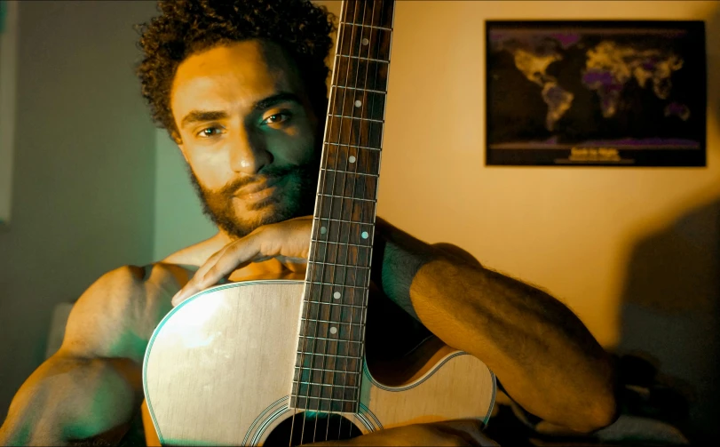 a man is holding a guitar while looking up at it