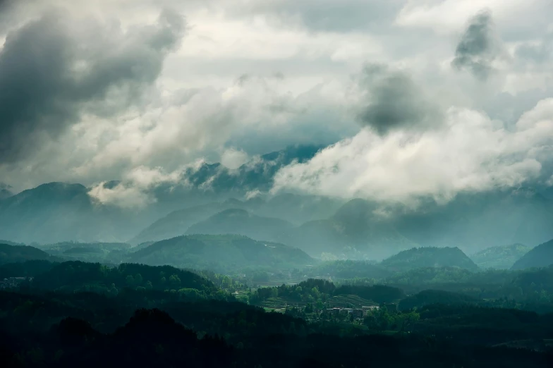 an overcast sky in a forested mountain range