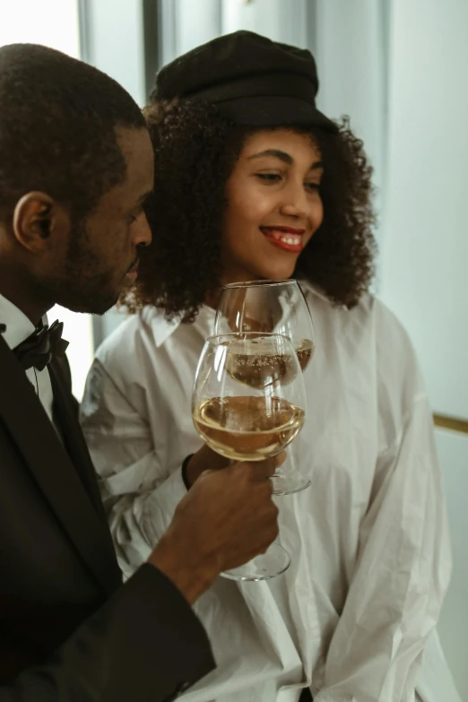 man in tuxedo next to smiling woman and a glass of wine