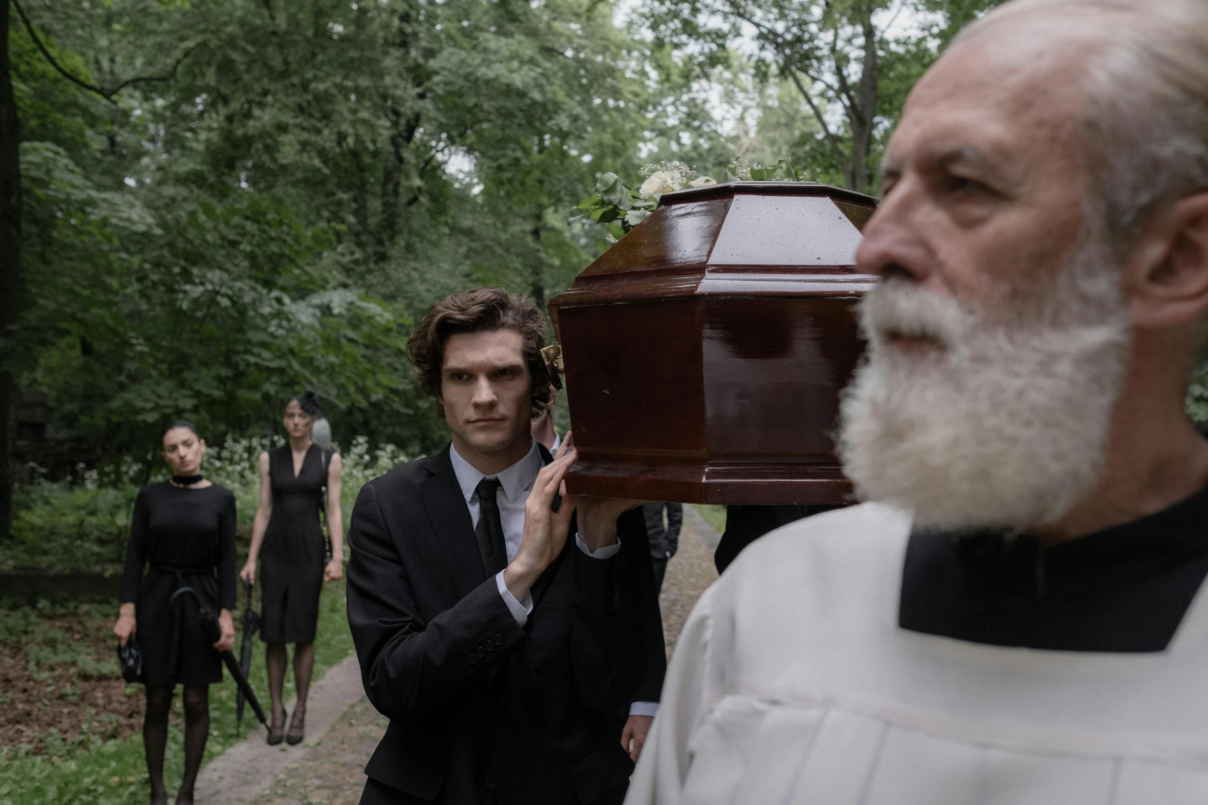 two people stand in front of a grave while two other people look on