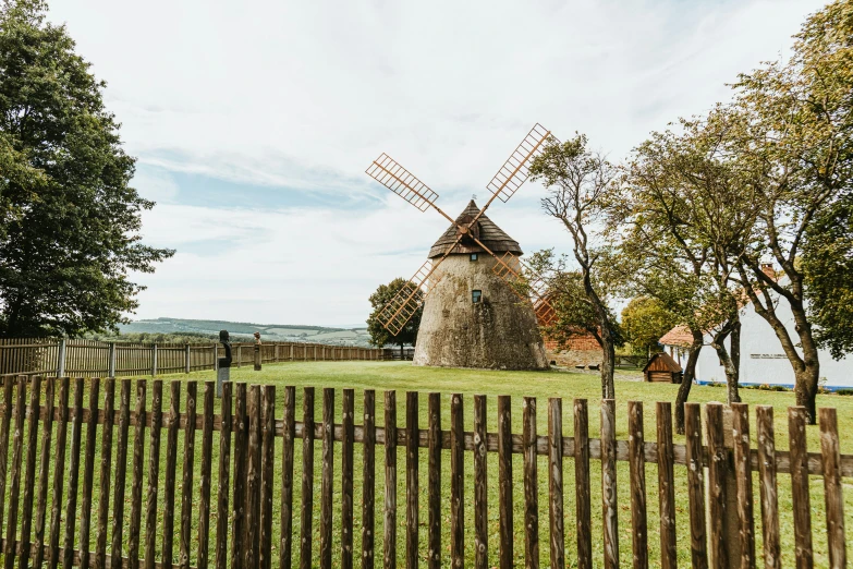 a windmill in a grassy field next to a fence