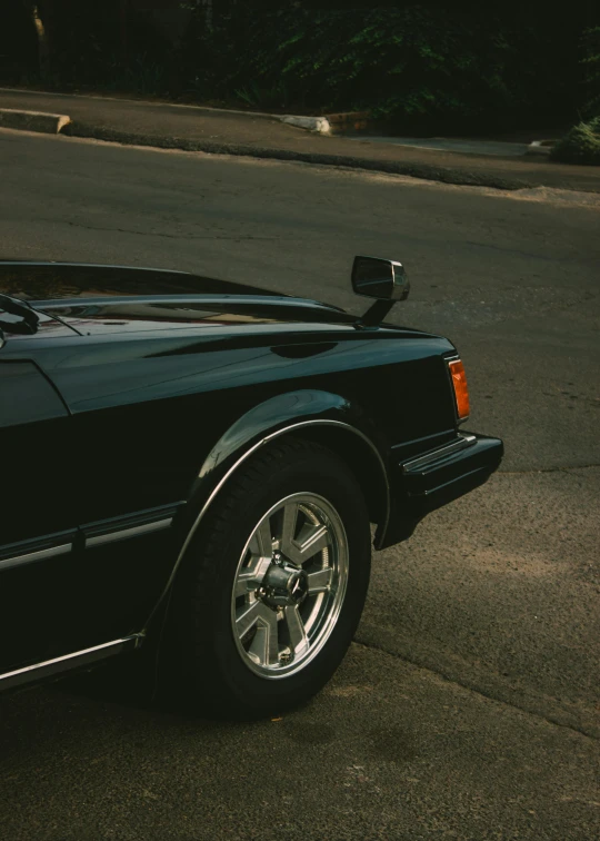 an old, shiny car that is parked on a street