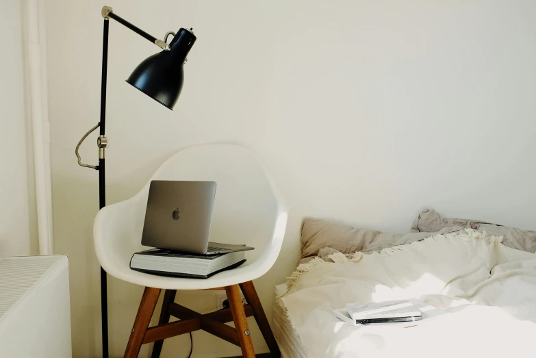 an apple laptop on a table near a bed