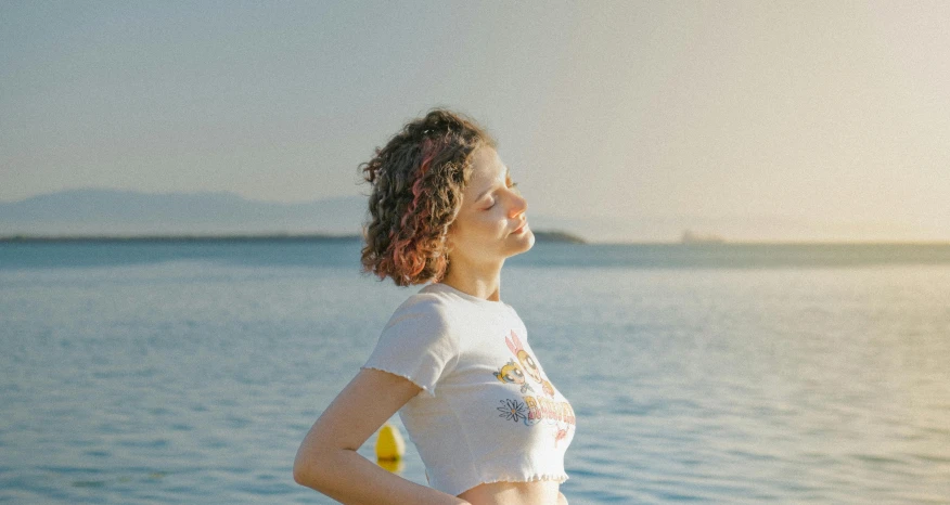 a woman is standing on the shore by the water