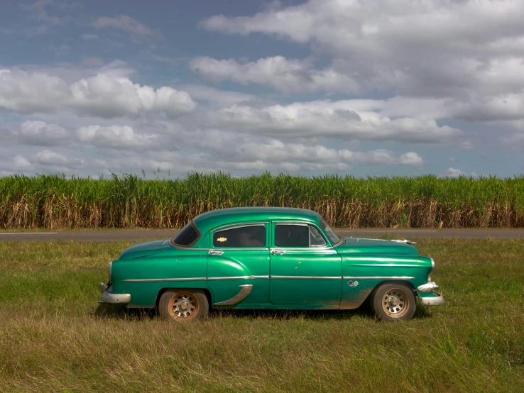 the old green car is sitting in the grass