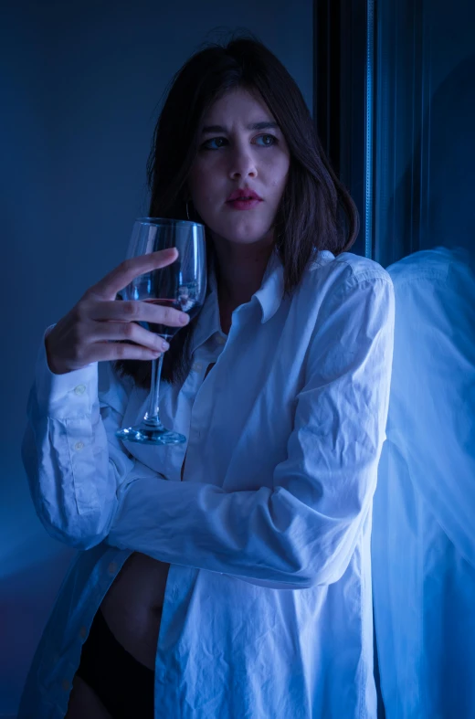 a woman holding a glass of wine in front of a wall