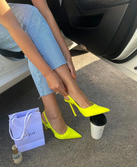 a person in striped shirt putting her yellow high heel shoes on a bag