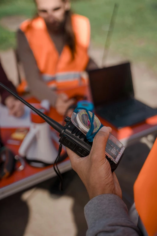 the hand is holding a smart phone near two laptops