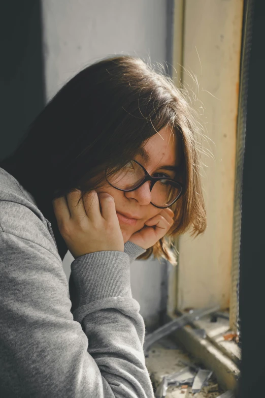 a young woman with glasses looking out the window