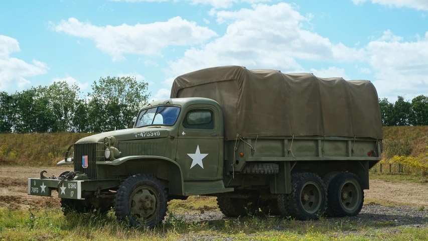 the large army truck is parked in the field