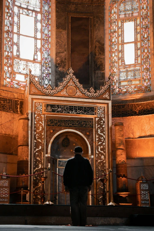 man in a traditional persian outfit standing in a mosque