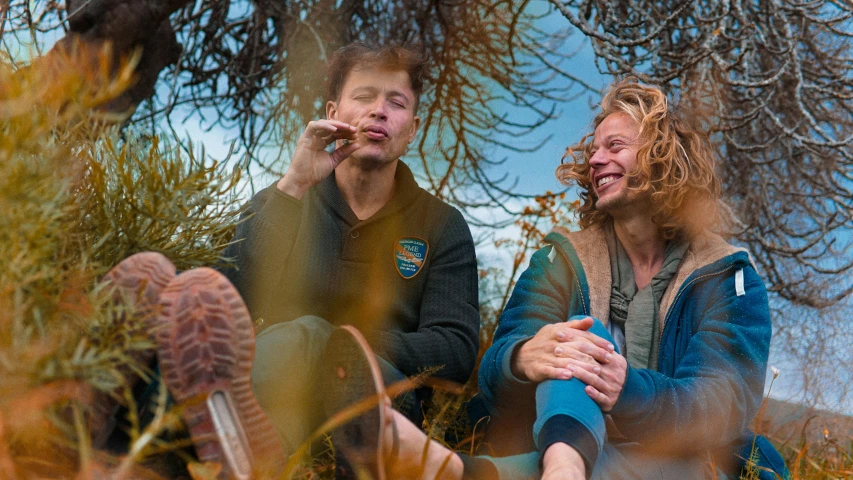 two people sitting outside with trees behind them