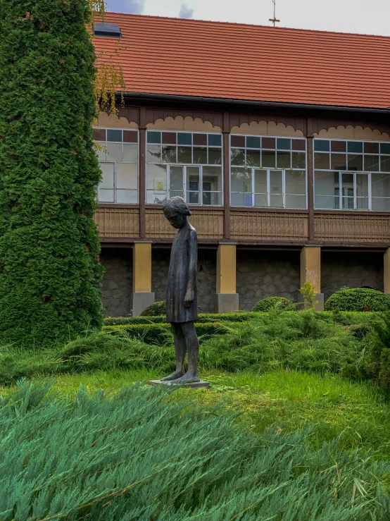 statue of man in front of apartment building near grassy area