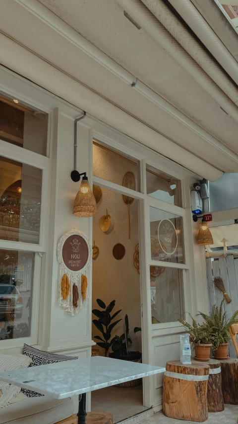 the exterior of a cafe with a white table and a white bench