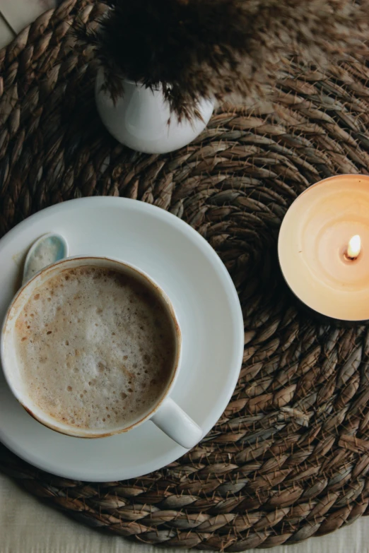 a cup of coffee and lit candle on a tray