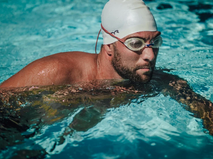 a man swimming in a swimming pool wearing goggles and swim hat