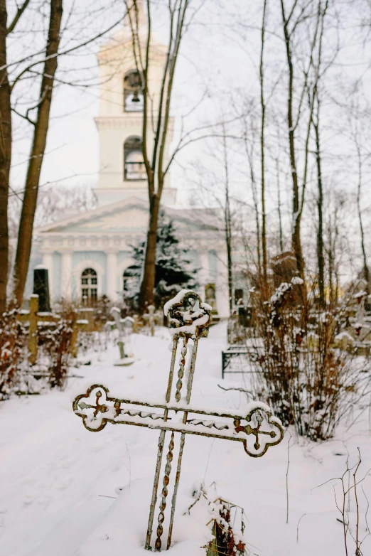 an ornate metal cross in the snow at a church