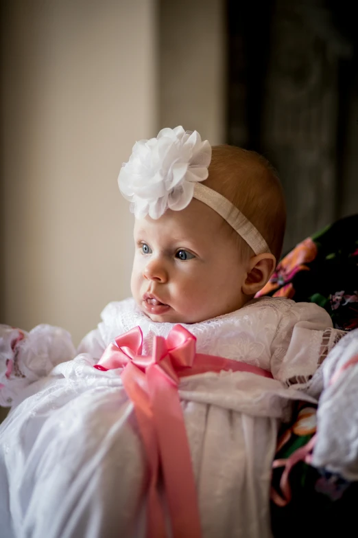 baby girl in pink sitting down with pink ribbon