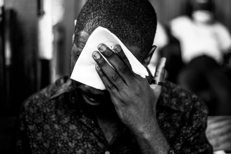 a man holding his head and napkin while sitting