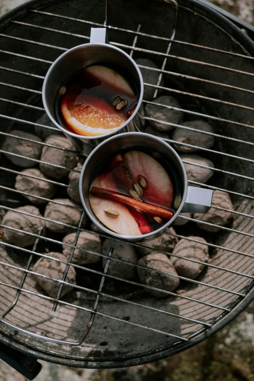 the two tea mugs are sitting on a charcoal barbecue grill