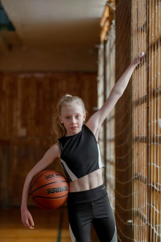 a girl holds a basketball by the net