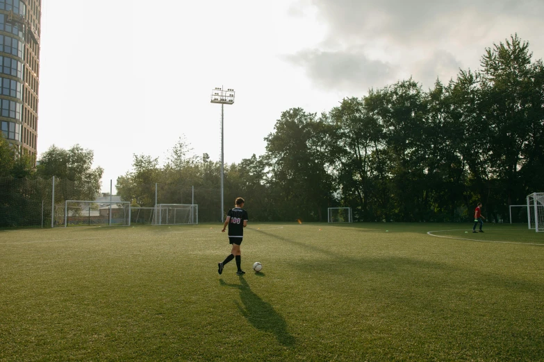 a boy in black uniform on a field playing soccer