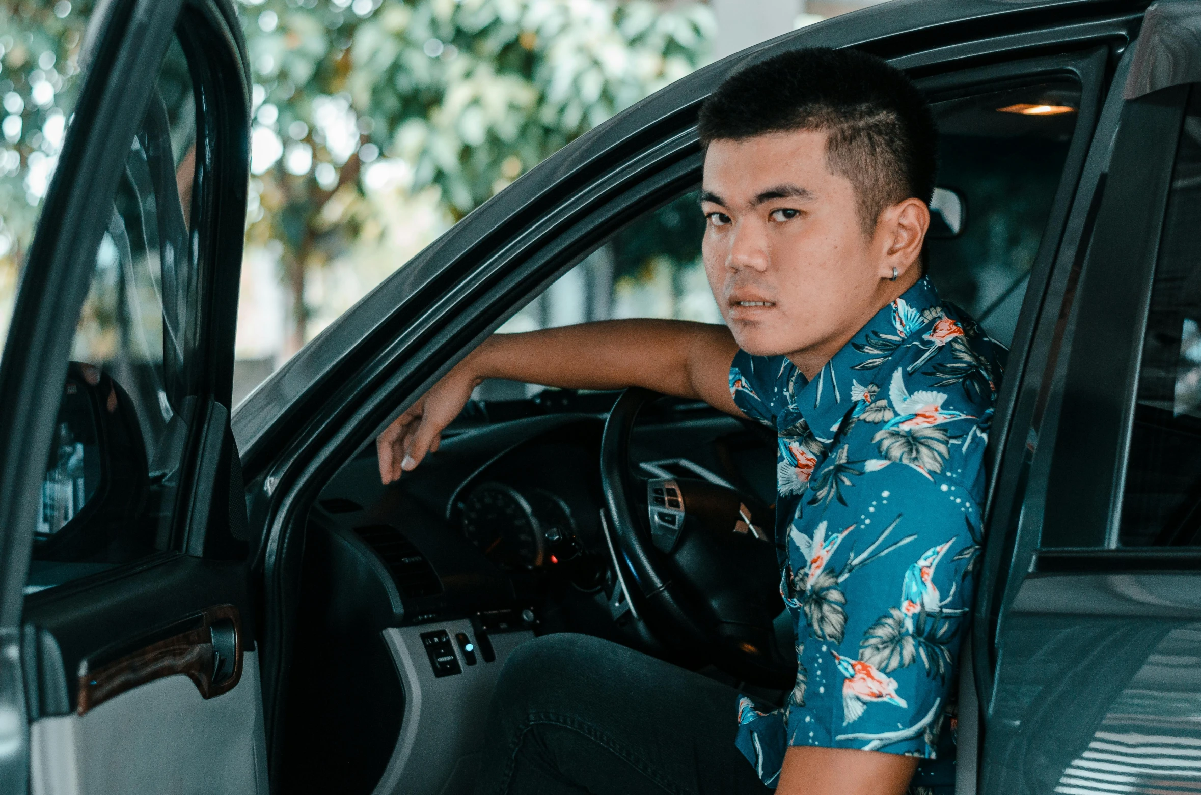 a man wearing a hawaiian shirt sitting in a car