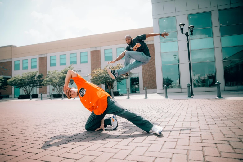 a man jumping over a skateboard on top of a person in a orange jacket