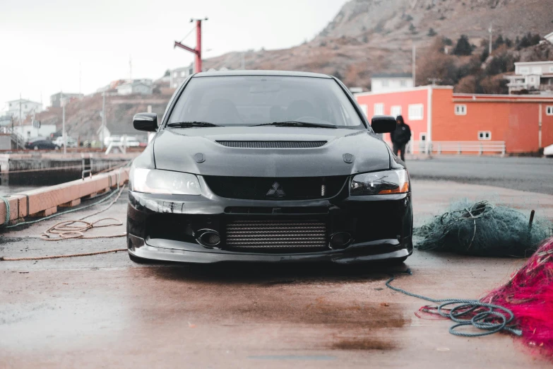 a black car on a wet road by a fence