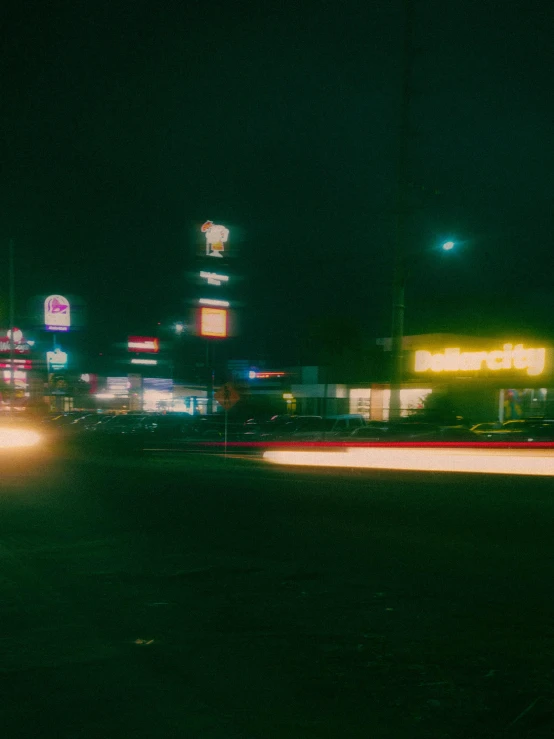 cars driving past a gas station at night