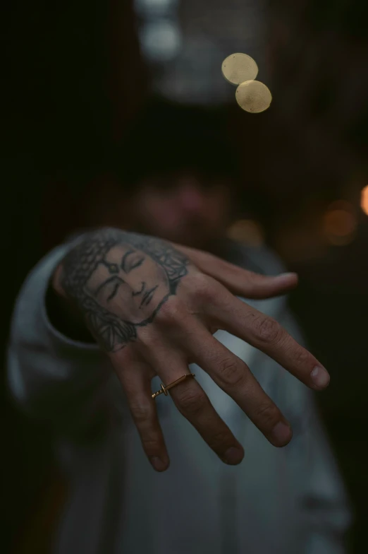 a tattooed man's arm is shown while holding his hand up