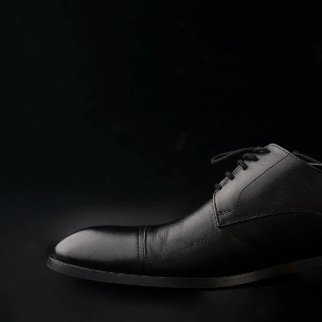 black leather shoes in low light with dark background