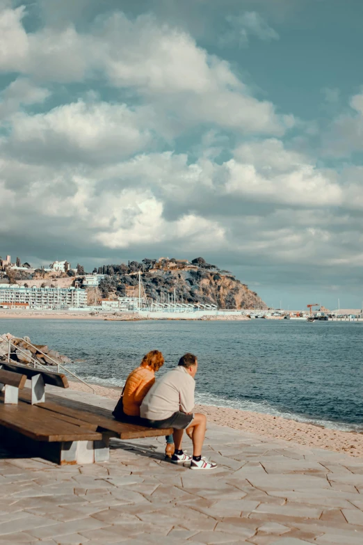 a man sitting on top of a bench near the ocean