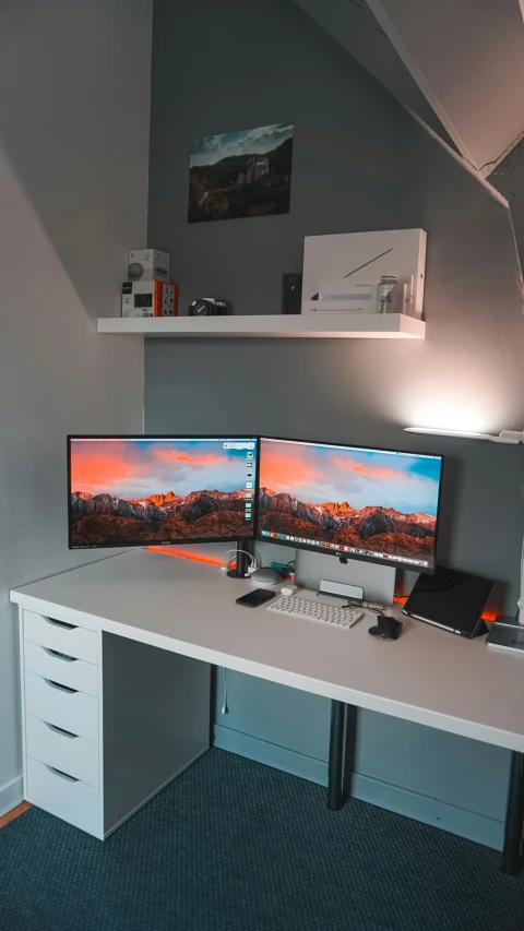 the view from inside an office shows two large monitors and a laptop on a white desk