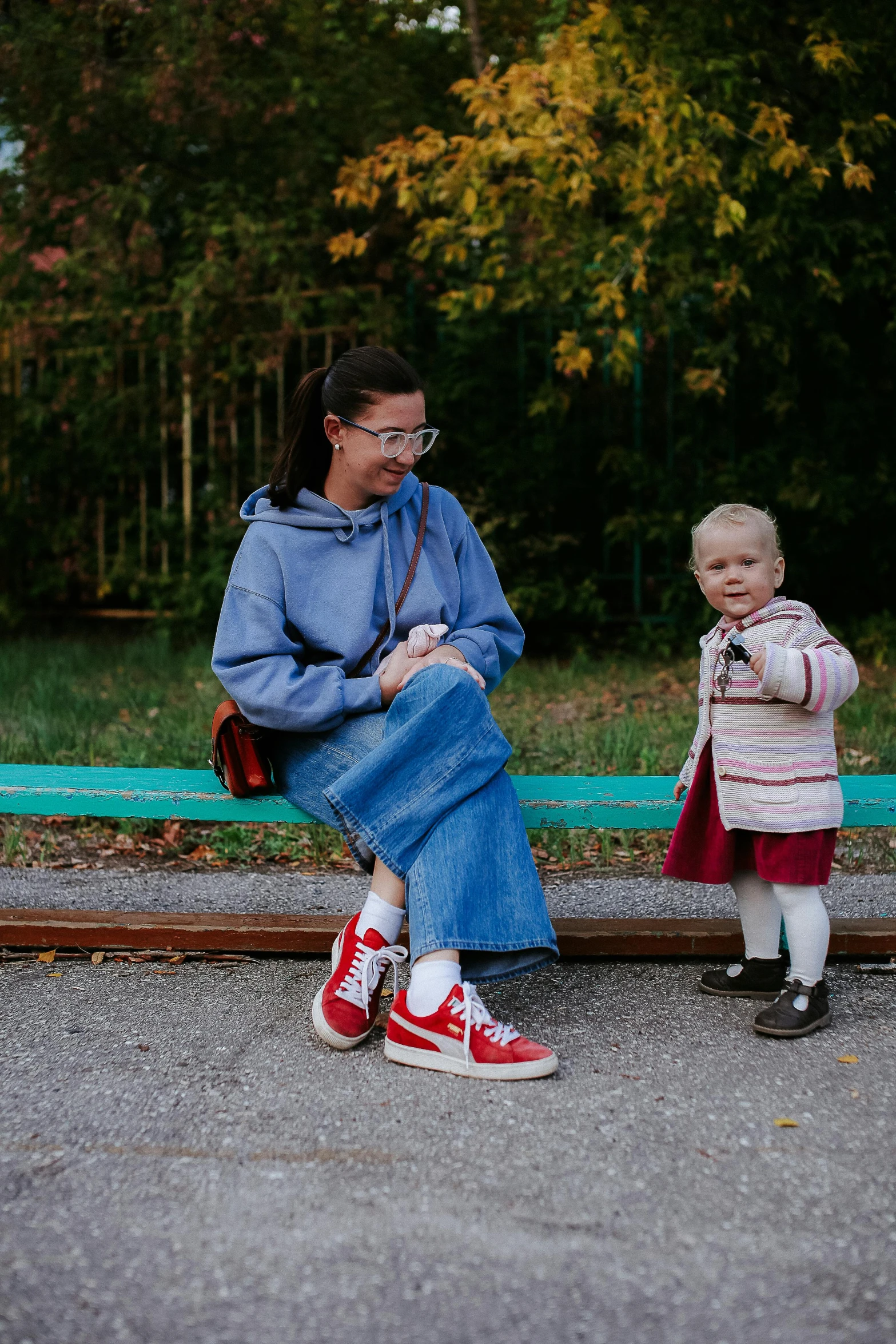 a little girl standing next to a woman with her feet crossed