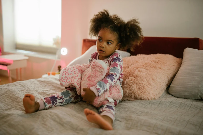 a small girl in pajamas on a bed with pillows