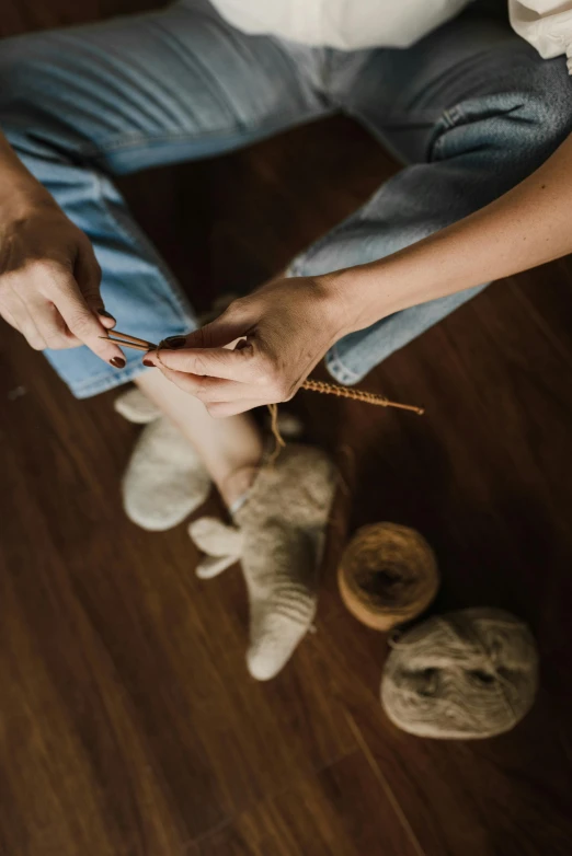 a person sitting on the floor with two balls of yarn