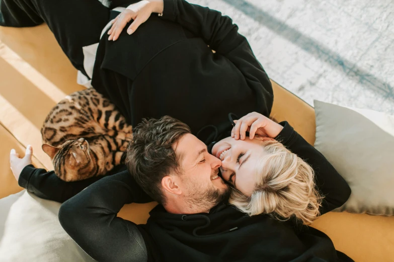 a man kisses the lips of his wife as they look at their pet