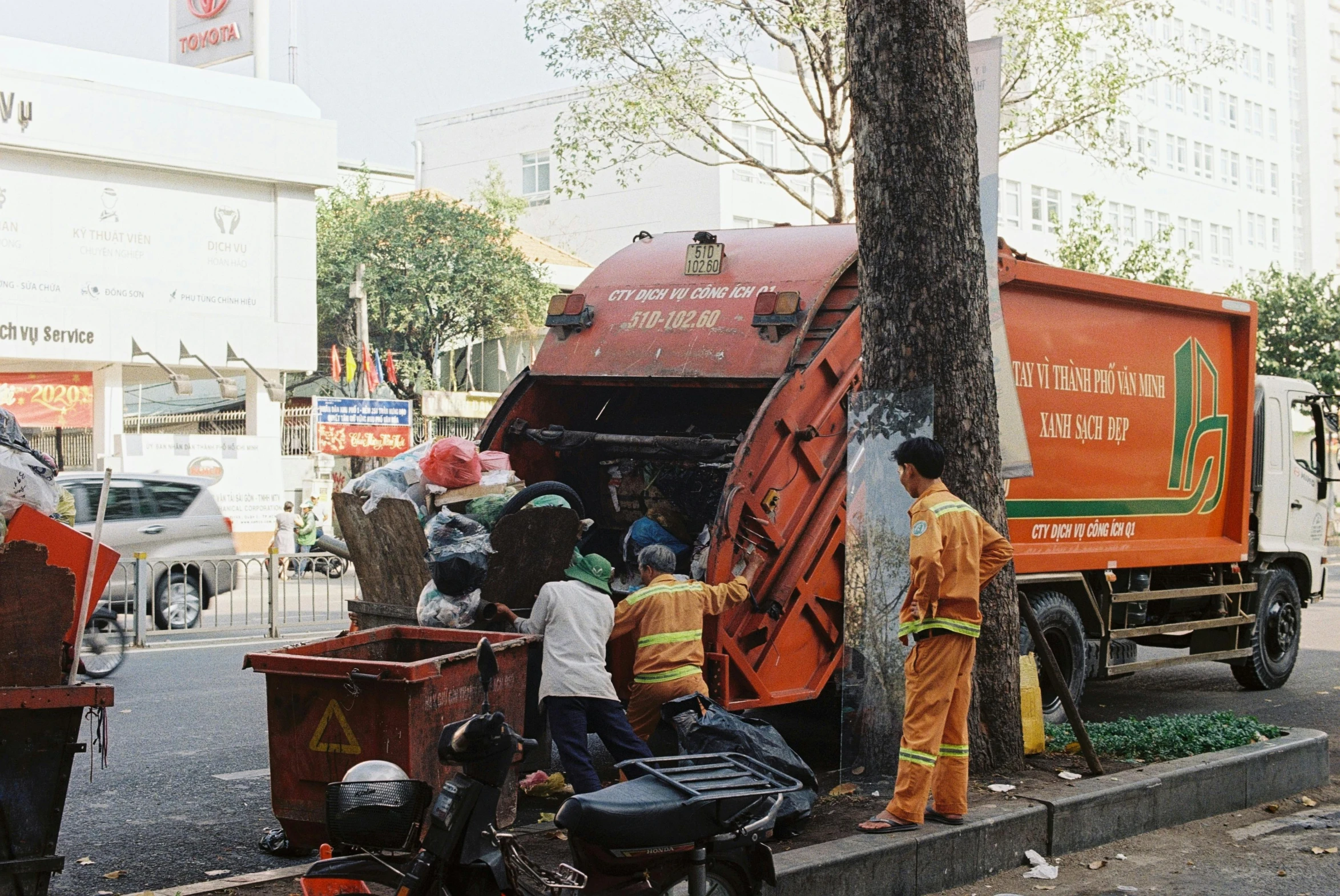 a group of men that are next to a garbage truck