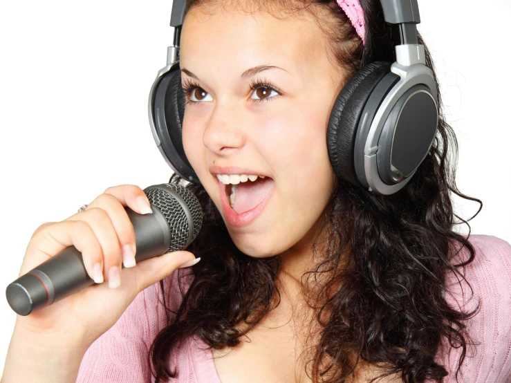 the woman with headphones is singing into a microphone