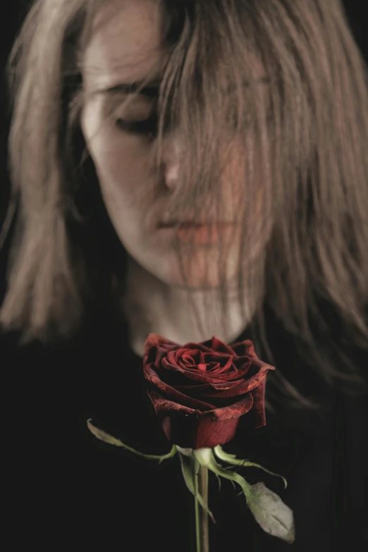 a woman with her eyes closed while holding a rose