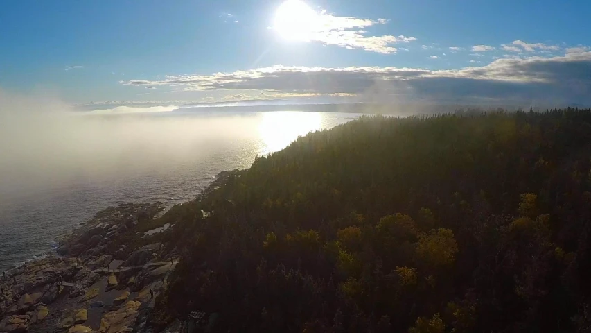 the sun shining in the distance over the water and trees