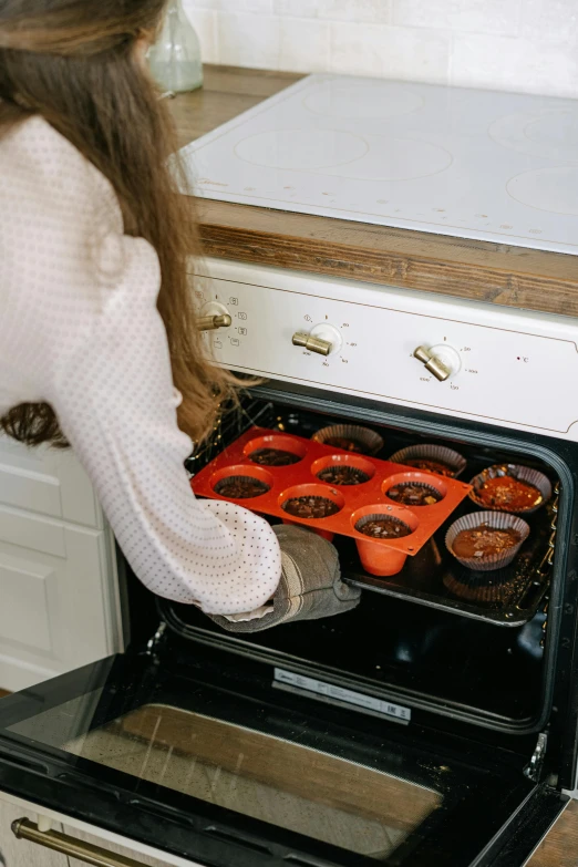 a woman places a tray with food into the oven