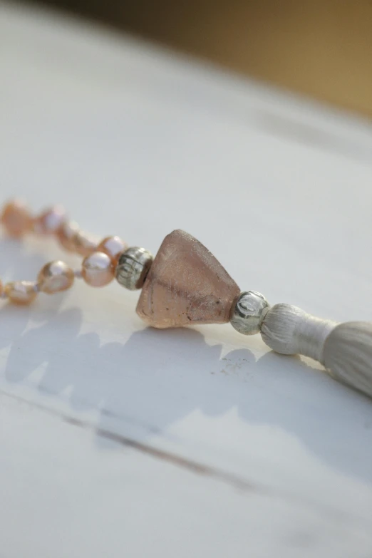 a tiny pink beaded earring with a tassel