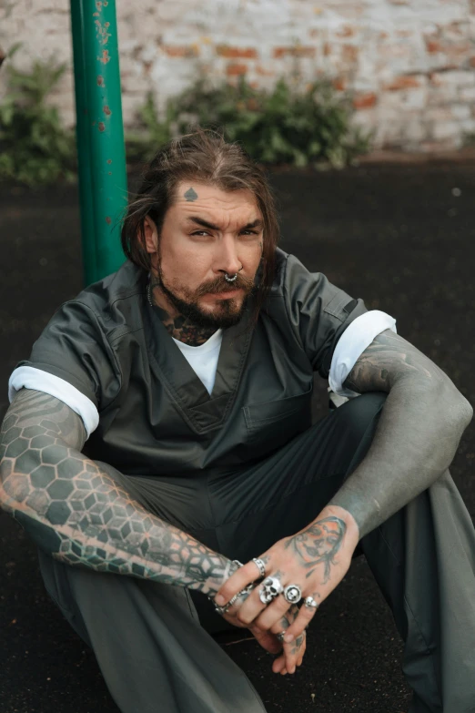 a man sitting on the ground with tattoos on his arms