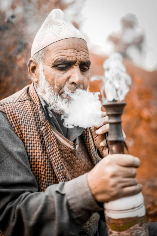 a man smoking with a large pipe near trees