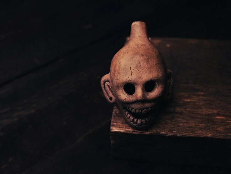 an old, creepy looking toy head sitting on top of a wood table